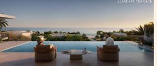 Poolside terrace of a Y Views villa at dusk, overlooking gardens and the Arabian Gulf.
