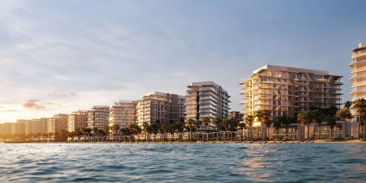 Fahid Beach Residences on the shoreline of Fahid Island, seen from the water at dusk.