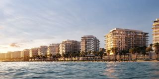 Fahid Beach Residences on the shoreline of Fahid Island, seen from the water at dusk.