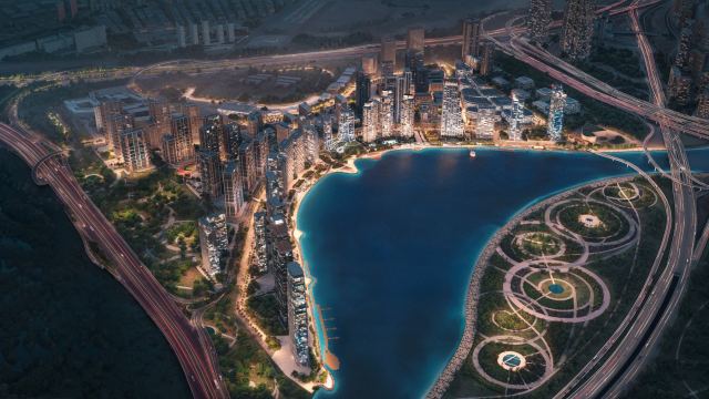 Evening aerial of the Dubai Design District waterfront, with the inland beach and landscaped gardens along the edge