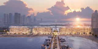 Dubai Harbour Residences seen from the water at sunset, a low-rise building running along the shoreline.