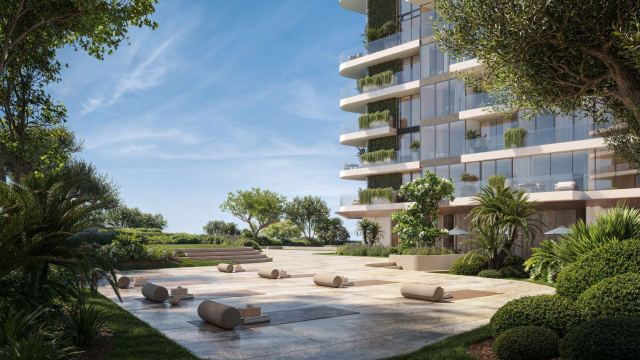 Landscaped gardens beside a waterfront tower at Dubai Maritime City