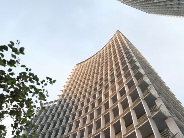Looking up the curved stone facade of Four Seasons Private Residences Dubai at DIFC.