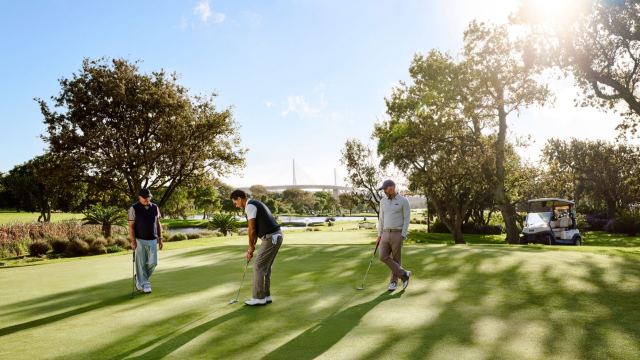Players on a tree-lined fairway at Hudayriyat Golf Estates.
