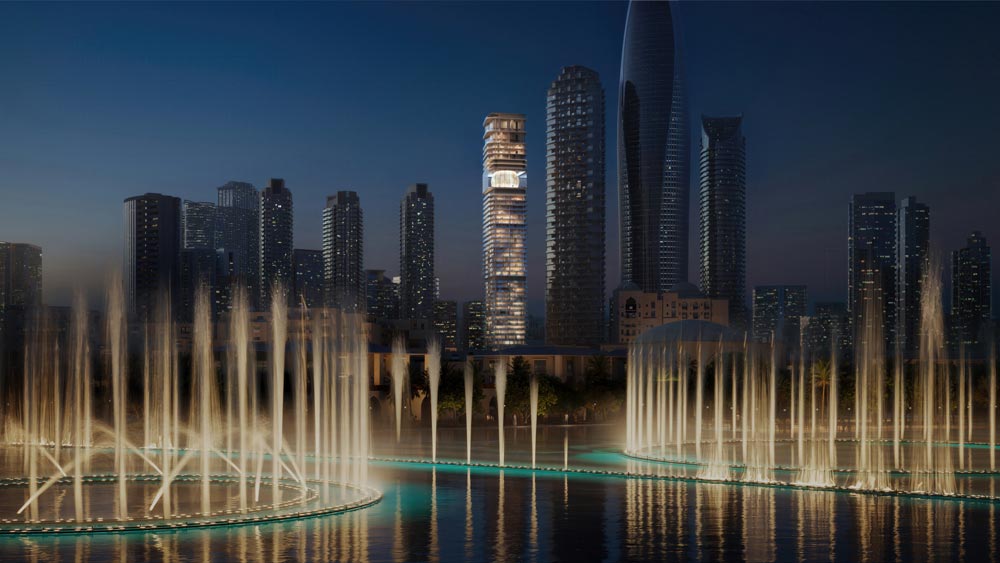 Inaura by Arada seen lit across the Dubai Fountain in Downtown Dubai at night.