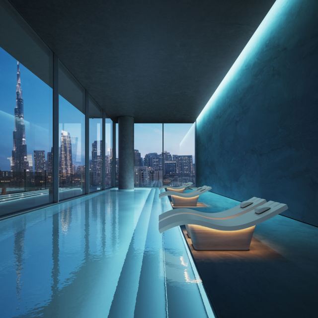 Indoor spa pool at Inaura with loungers and a city view.