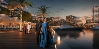 Marina promenade at Marsa Al Saadiyat at dusk, with yachts berthed alongside waterfront restaurants and apartment buildings.