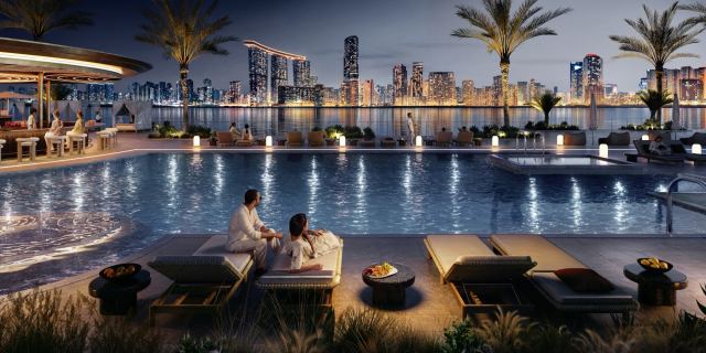 Beach club pool at Marsa Al Saadiyat at night, facing the Abu Dhabi skyline across the water.