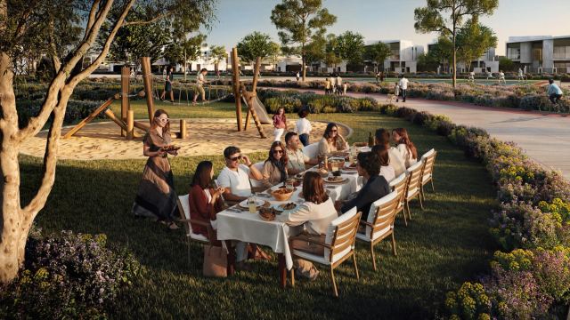 Family gathering in a neighbourhood park at Marsa Al Saadiyat, with townhouses and a cycling path behind.