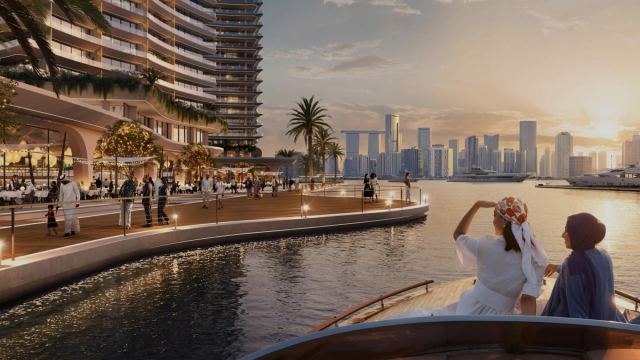 Waterfront promenade and residential tower at Marsa Al Saadiyat seen from the water at sunset.