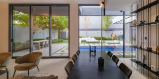 Living and dining area of a Masaar 3 home, opening to the garden and pool.