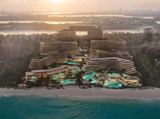 The Meriva Collection at sunrise, showing the curved terraces of Meriva Sunset above the pool decks.