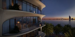 A balcony at Ocean House at dusk, looking across the water to the Burj Al Arab and the Dubai skyline.