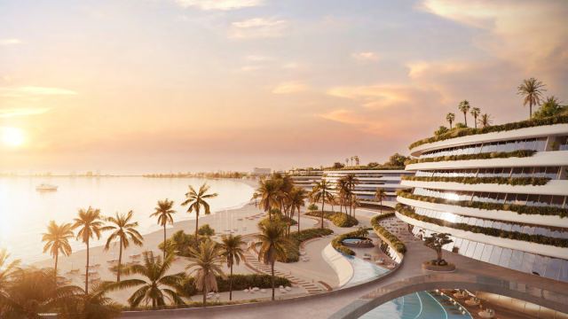 Sunset over the waterfront promenade at Palm Jebel Ali, with terraced buildings above the beach