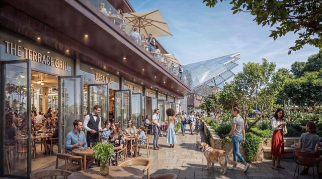 Terrace café and retail street at Sobha Sanctuary, with families dining under umbrellas among the trees.