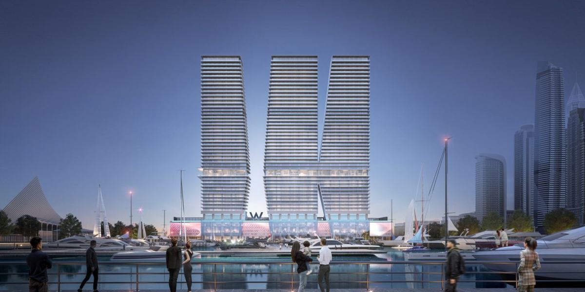 The three towers of W Residences at Dubai Harbour at dusk, seen from across the marina.