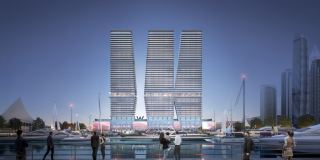 The three towers of W Residences at Dubai Harbour at dusk, seen from across the marina.