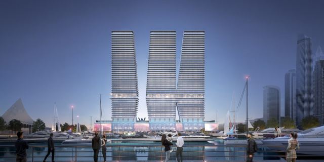 The three towers of W Residences at Dubai Harbour at dusk, seen from across the marina.